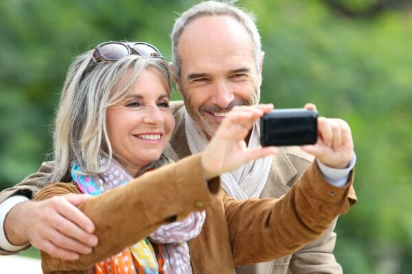Traveling senior couple taking selfie together after dental implant consultation